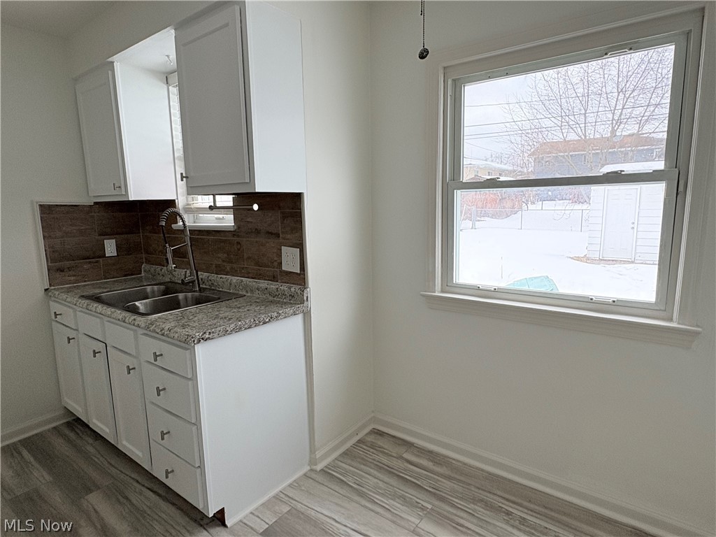 15521 Corkhill Road Maple Heights, OH 44137 - Photo 6 of 33 Kitchen featuring white cabinetry, tasteful backsplash, healthy amount of natural light, and light wood finished floors