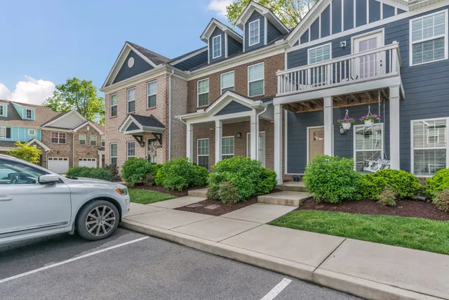a view of a big house with a big yard and potted plants and large trees