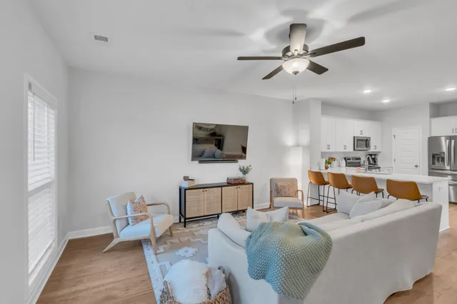 a living room with furniture a flat screen tv and kitchen view