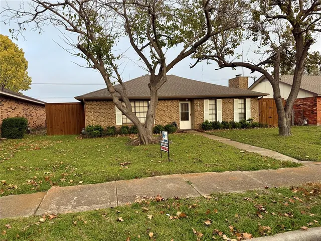 a front view of a house with a garden and trees