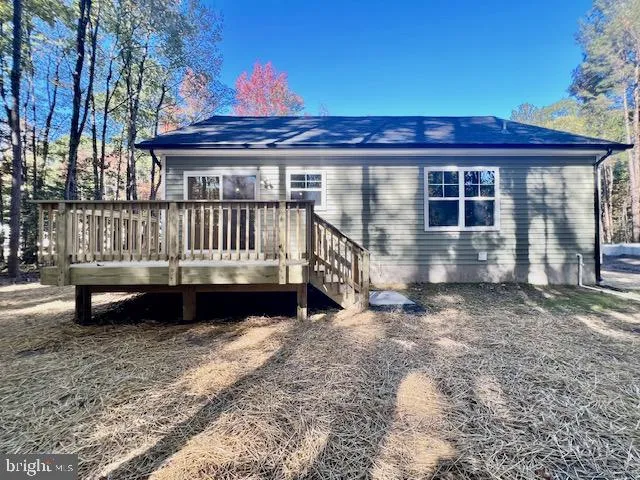 a view of a house with a wooden deck and a yard