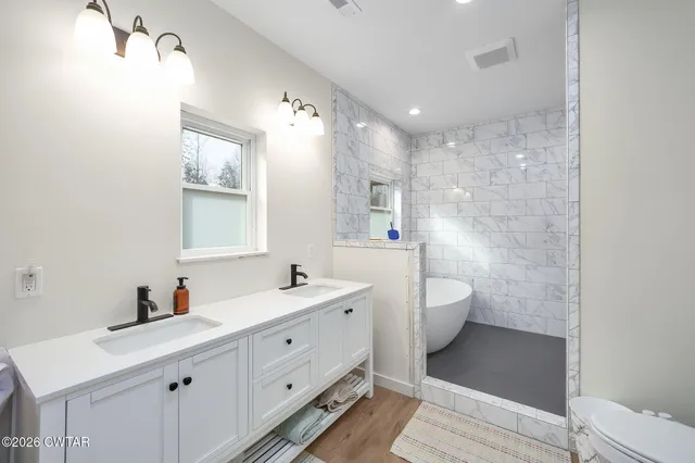 a spacious bathroom with a double vanity sink toilet mirror and bathtub