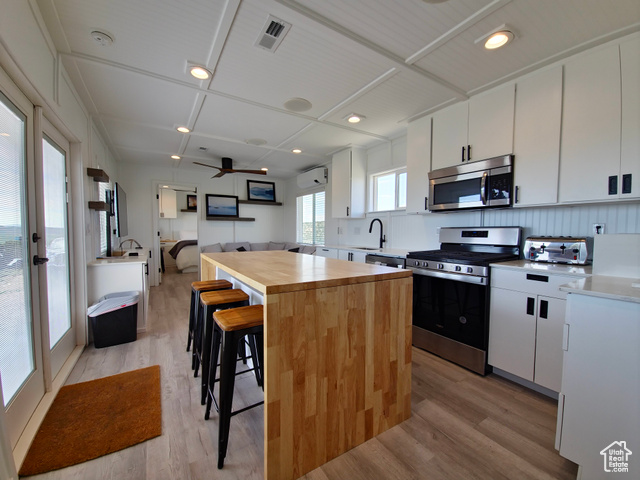 900 Altamont Road Evanston, WY 82930 - Photo 7 of 27 Kitchen with stainless steel appliances, light wood finished floors, a kitchen island, wooden counters, and a breakfast bar