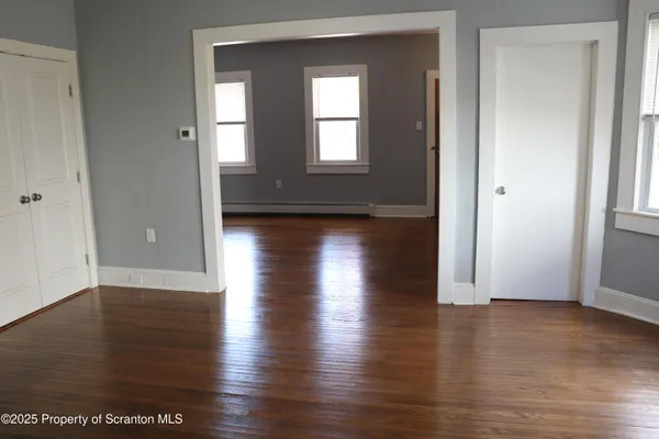 an empty room with wooden floor and windows