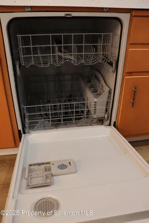 a view of a refrigerator in kitchen and an empty room