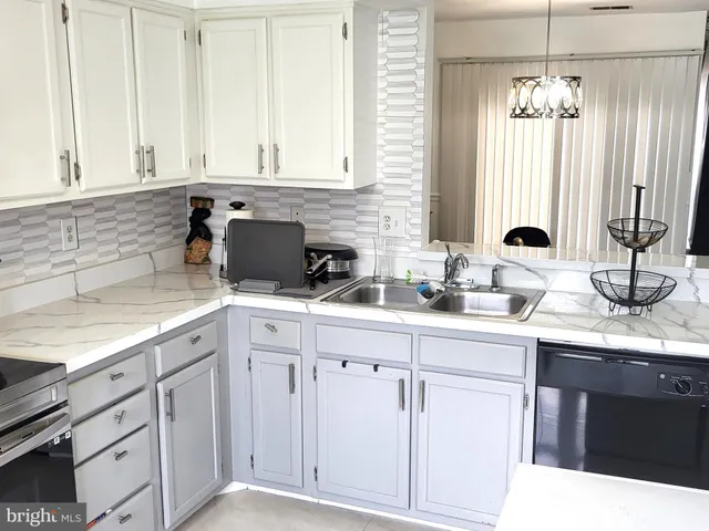 a kitchen with white cabinets and sink