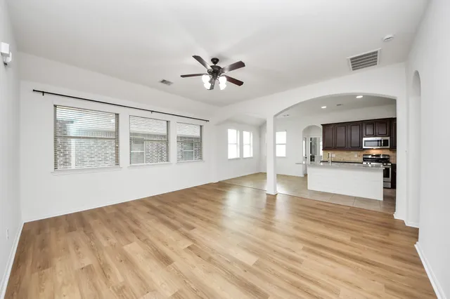 a view of an empty room with kitchen and window