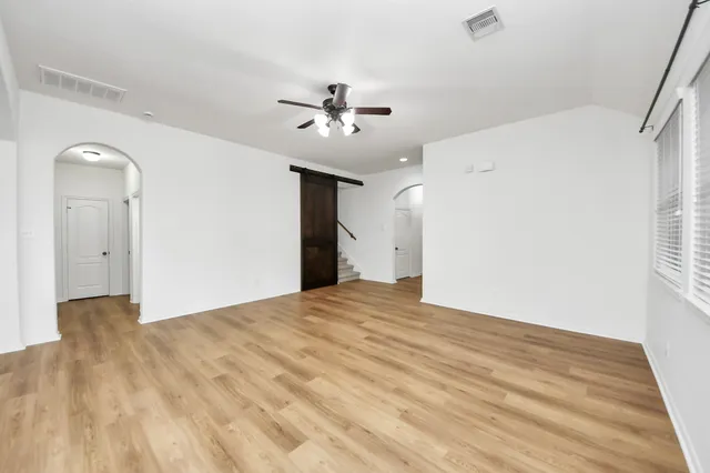 a view of empty room with wooden floor and fan