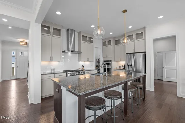 a kitchen with granite countertop a stove a sink a dining table and chairs
