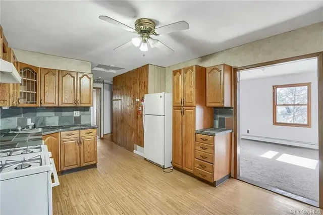 a kitchen with stainless steel appliances granite countertop a refrigerator a stove top oven a sink dishwasher and white cabinets with wooden floor