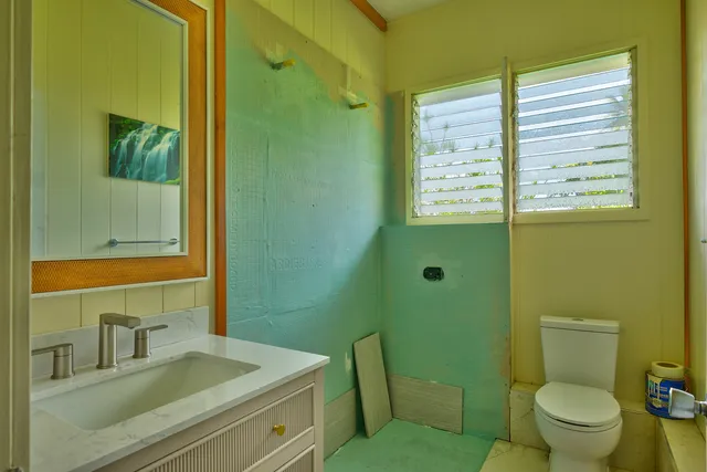 a bathroom with a granite countertop toilet a sink and a mirror