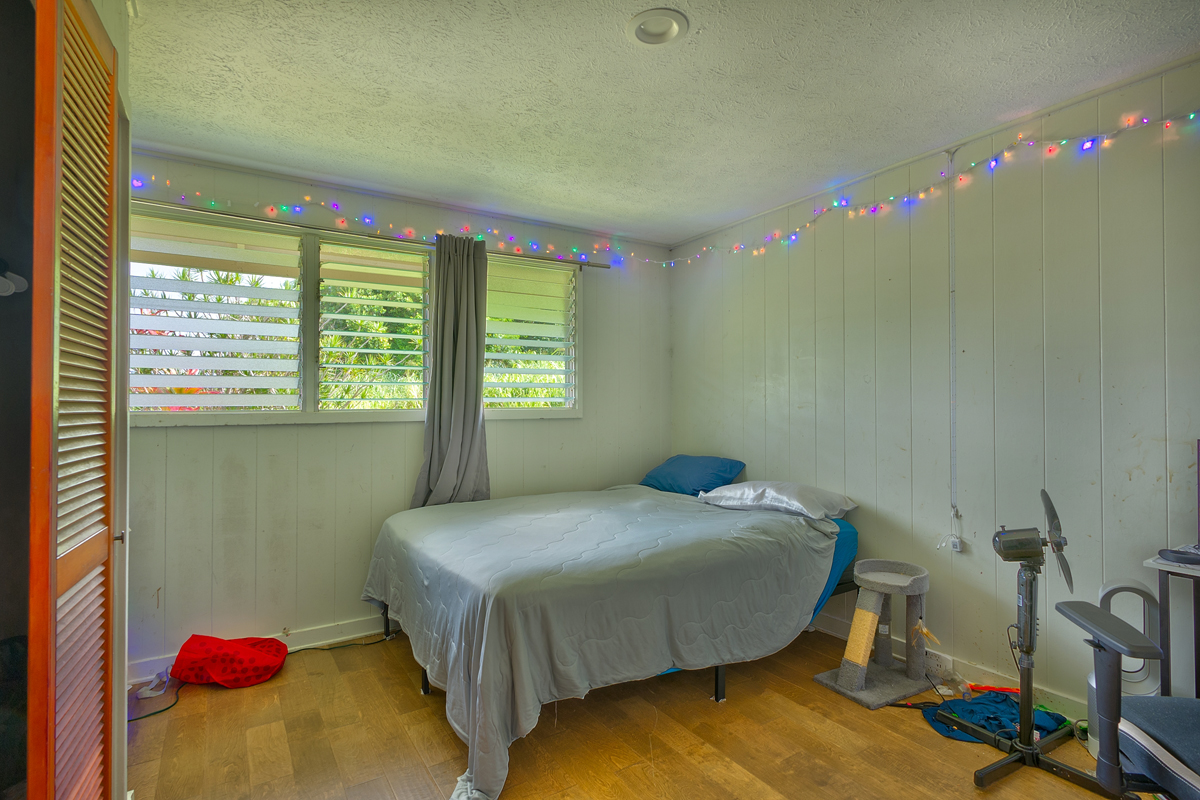82-1019 KOA Road Captain Cook, HI 96704 - Photo 10 of 17 a bedroom with a bed and a chandelier