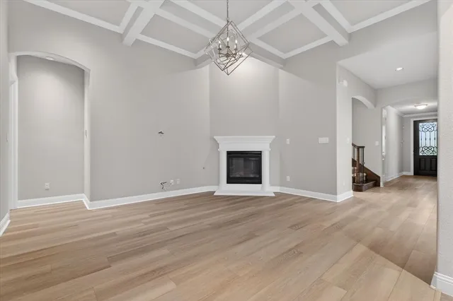 a view of an empty room with wooden floor and a fireplace