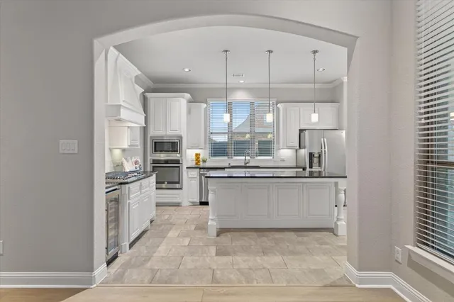 a kitchen with stainless steel appliances kitchen island granite countertop a stove a sink and white cabinets