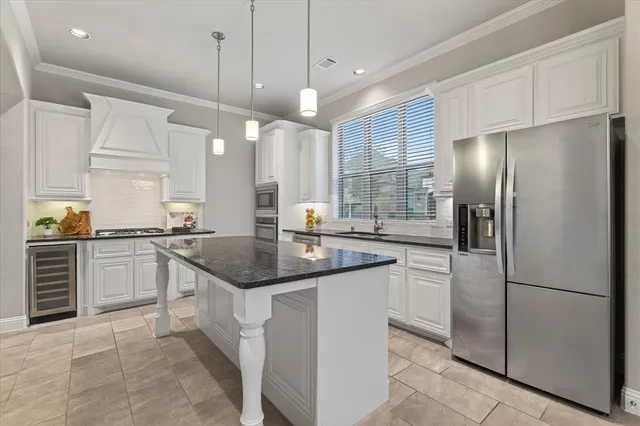 a kitchen with stainless steel appliances granite countertop a sink a stove a refrigerator and island with wooden floor