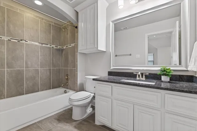 a bathroom with a granite countertop sink a toilet a mirror and bathtub