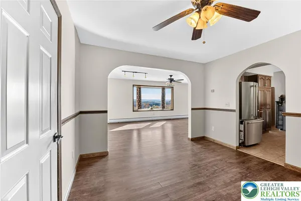 an empty room with wooden floor chandelier fan and windows