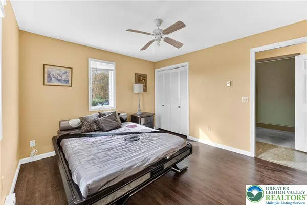a spacious bedroom with a bed a chandelier with dresser and mirror