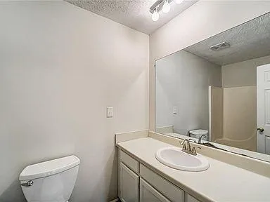 a bathroom with a granite countertop sink toilet and mirror