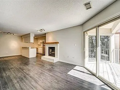 a view of a livingroom with a fireplace wooden floor and window