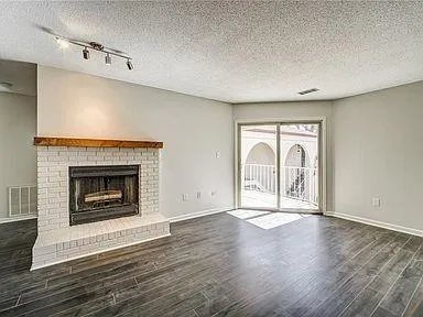 a view of an empty room with glass door and wooden floor