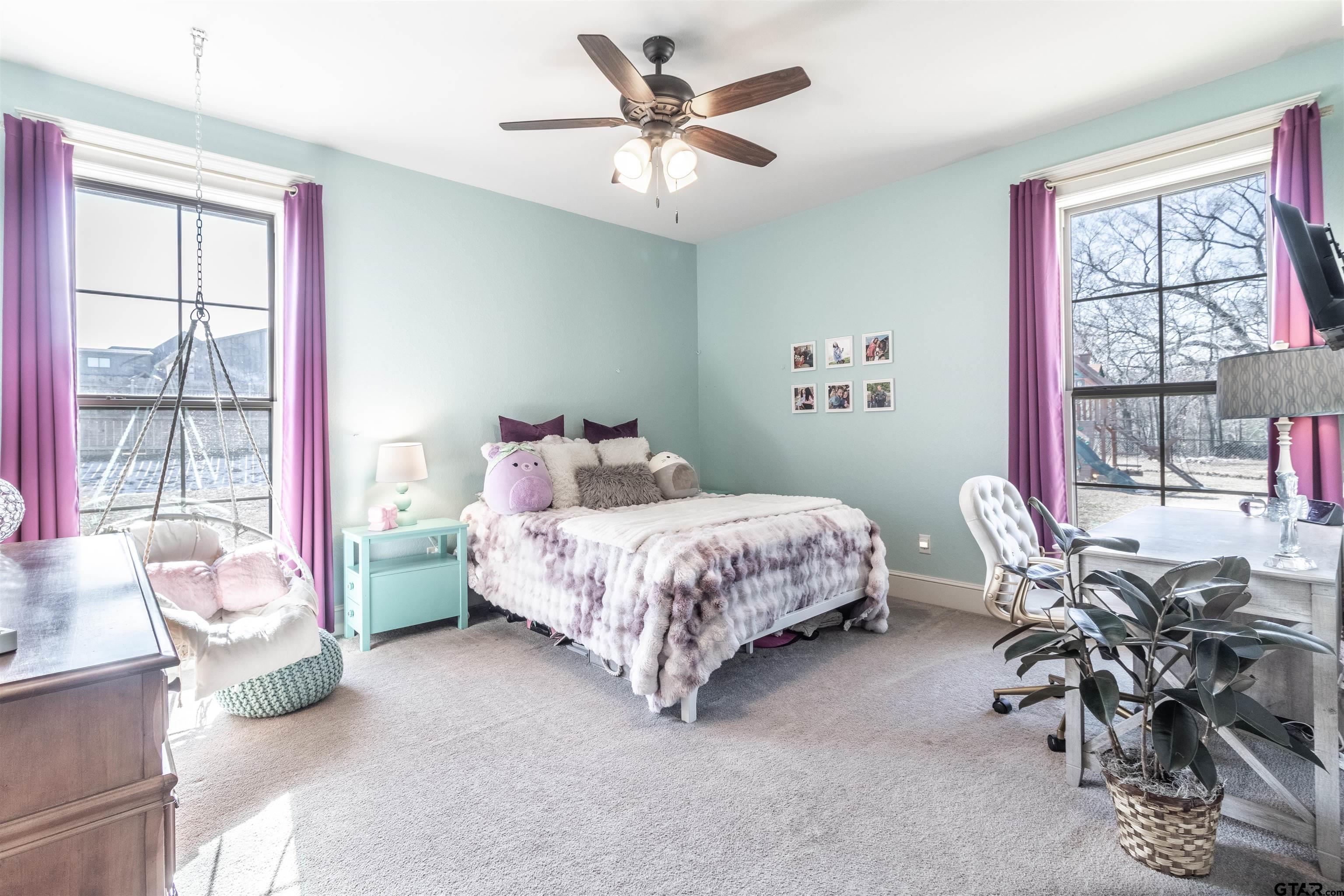 a bedroom with a bed a desk and chair with window