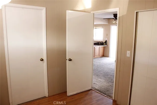 a view of a hallway with wooden floor and a bathroom