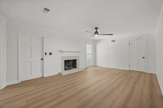 a view of empty room with wooden floor and fireplace