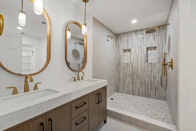 a bathroom with a double vanity sink mirror and shower