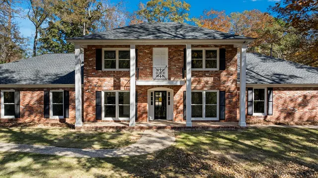 front view of a brick house with a large window and potted plants