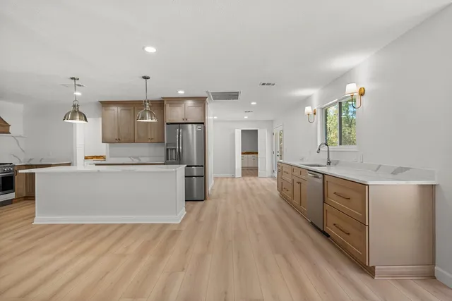 a large kitchen with kitchen island a sink stainless steel appliances and white cabinets