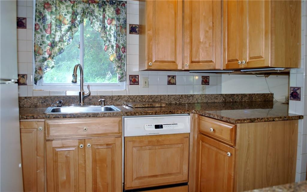 228 Bascom Avenue Pittsburgh, PA 15214 - Photo 10 of 24 Kitchen: featuring granite countertops, goose neck faucet, dishwasher, plenty of cabinets, under cabinet lighting, tile backsplash, gas stove, microwave, refrigerator, and views of the back yard!