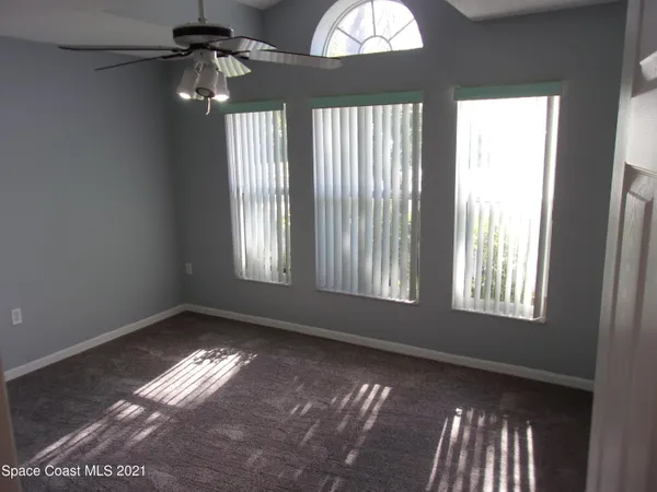 an empty room with windows and fan