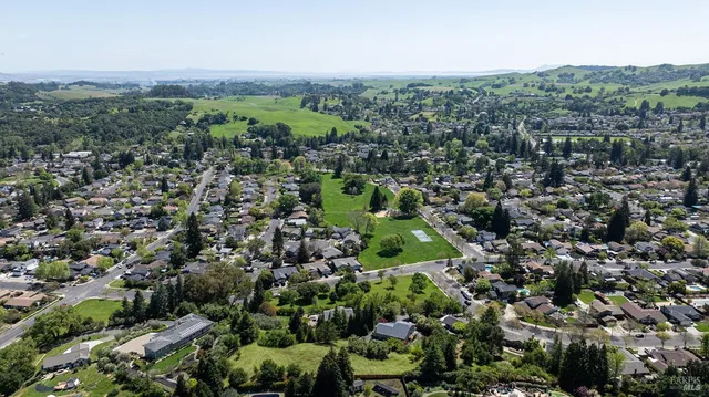 an aerial view of residential houses with outdoor space and trees