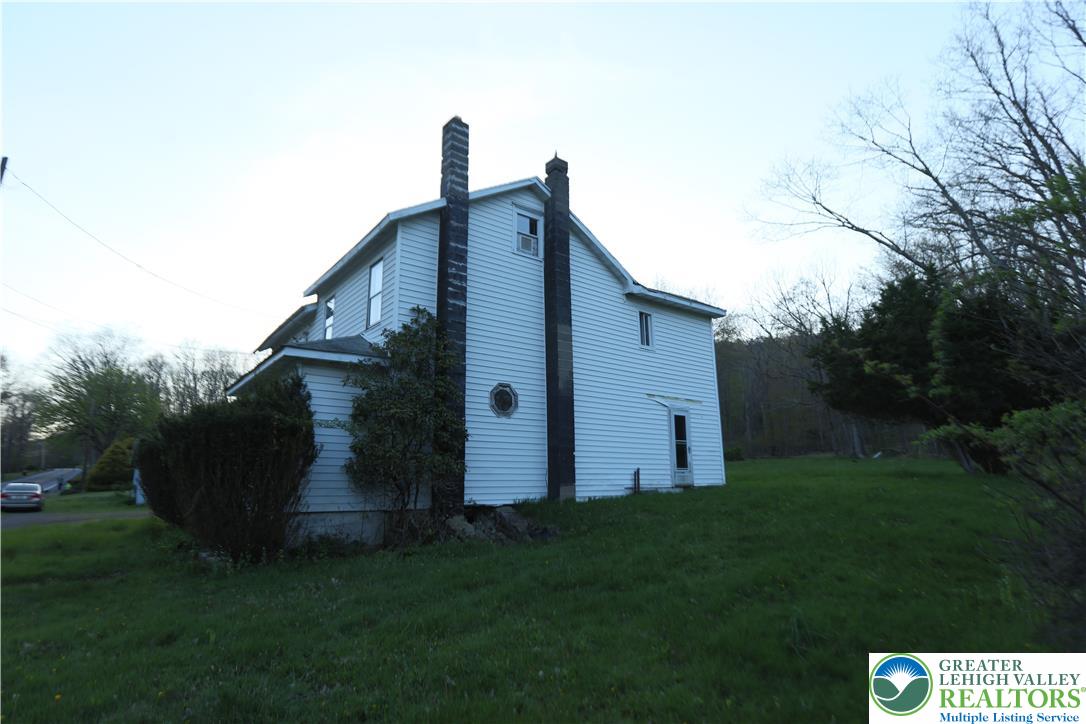 5444 Quakake Road Weatherly, PA 18255 - Photo 6 of 21 A classic white-sided residence with tall chimneys sits on a sloping lawn, bordered by mature trees.