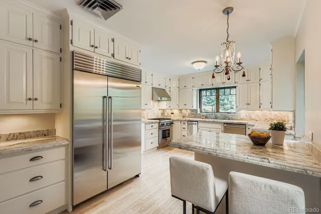 a kitchen with stainless steel appliances granite countertop a sink a stove and refrigerator