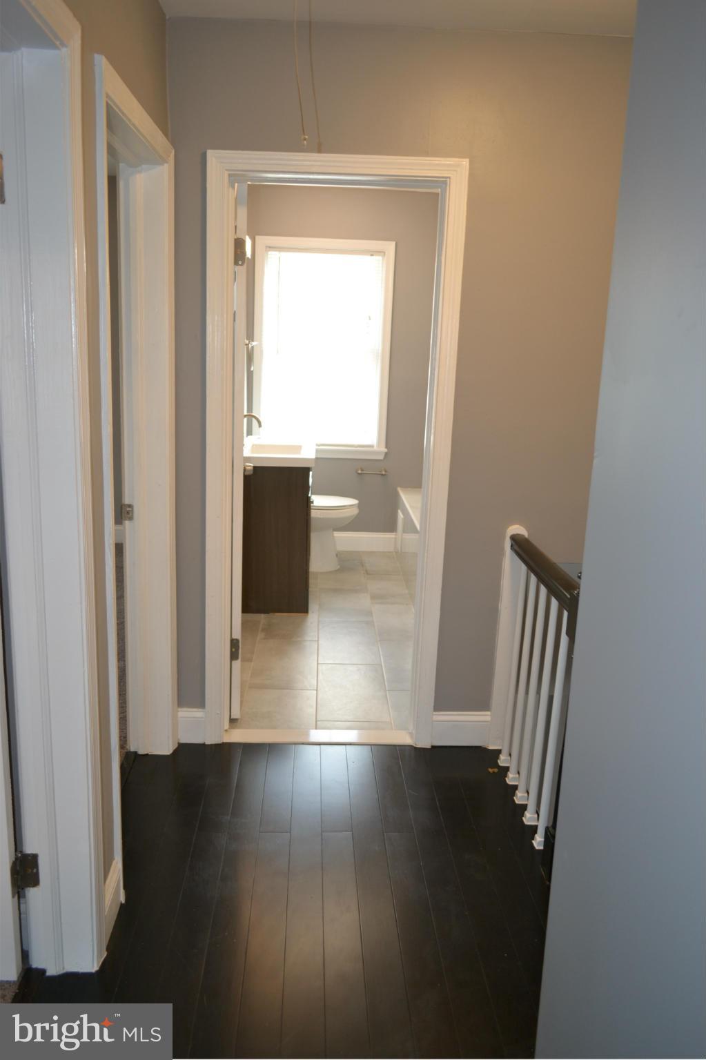 5216 Kelway Road Baltimore, MD 21239 - Photo 8 of 28 a view of a hallway with wooden floor and a living room