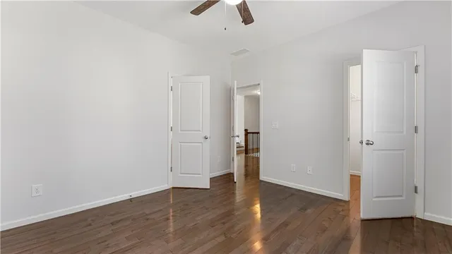an empty room with wooden floor and ceiling fan