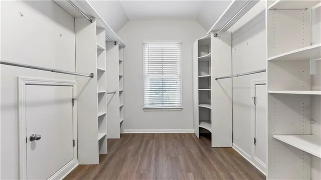 an empty room with wooden floor and fan