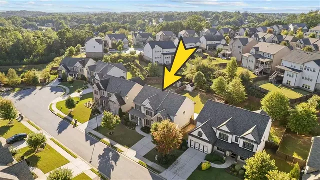an aerial view of a house with swimming pool and large trees