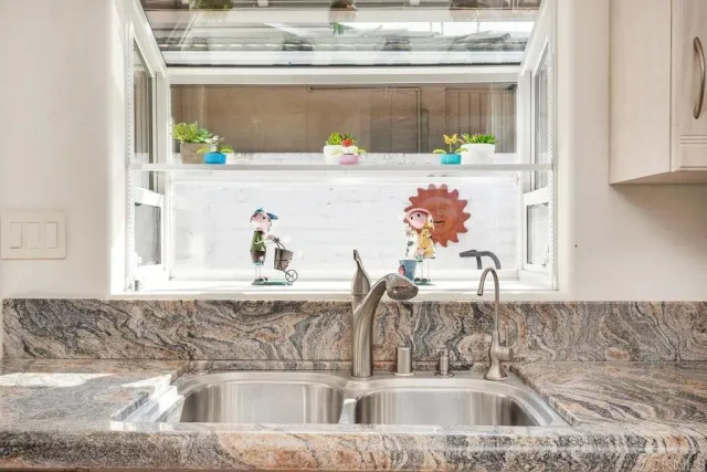 a kitchen sink with a granite countertop and white cabinets next to it