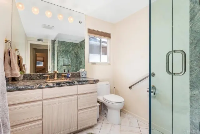 a bathroom with a granite countertop toilet sink and mirror