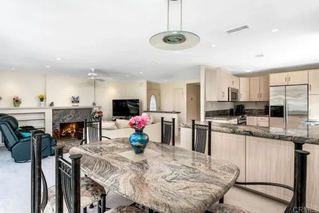 a kitchen with stainless steel appliances kitchen island granite countertop a table chairs and a refrigerator