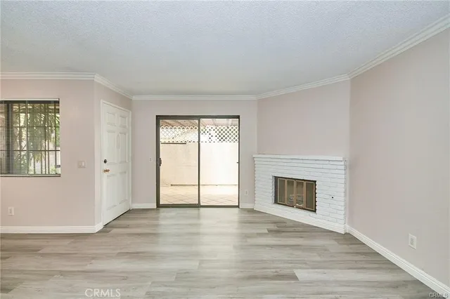 an empty room with wooden floor a fireplace and windows