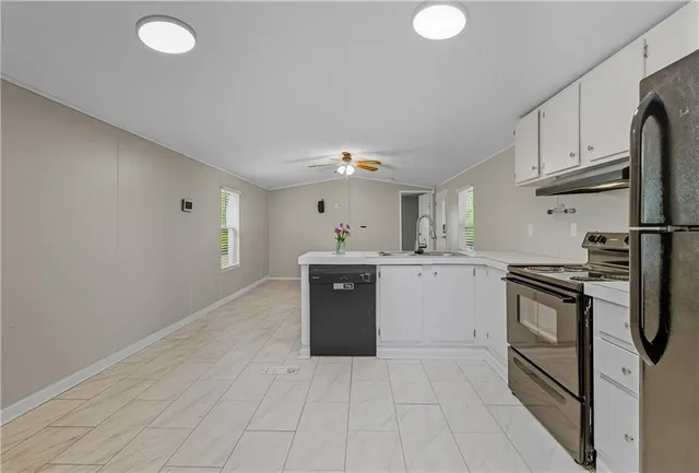 a view of an empty room with window and chandelier fan
