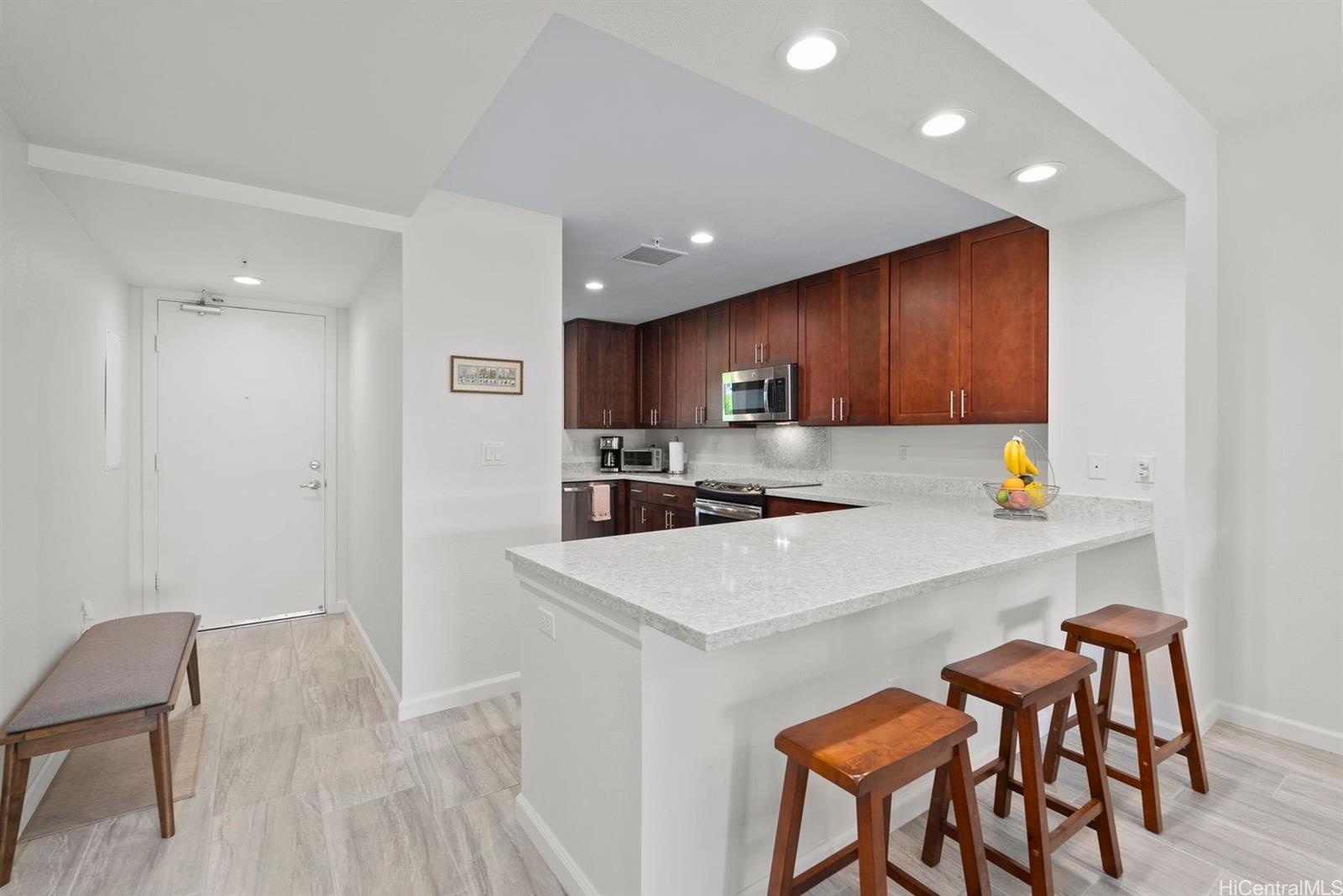 361 Kailua Road, Unit RD8205 Kailua, HI 96734 - Photo 4 of 23 a kitchen with a table chairs refrigerator and wooden cabinets