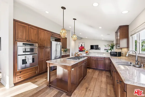 a kitchen with stainless steel appliances granite countertop a sink refrigerator and cabinets