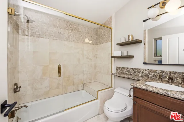 a bathroom with a granite countertop sink a toilet and shower