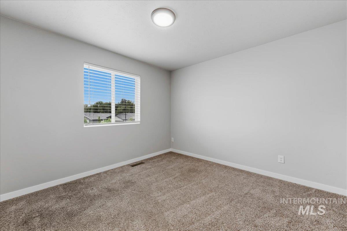 12475 West Victory Road Boise, ID 83709 - Photo 18 of 26 Neutral-toned carpeting paired with light gray walls, white trim, and a flush mount ceiling light