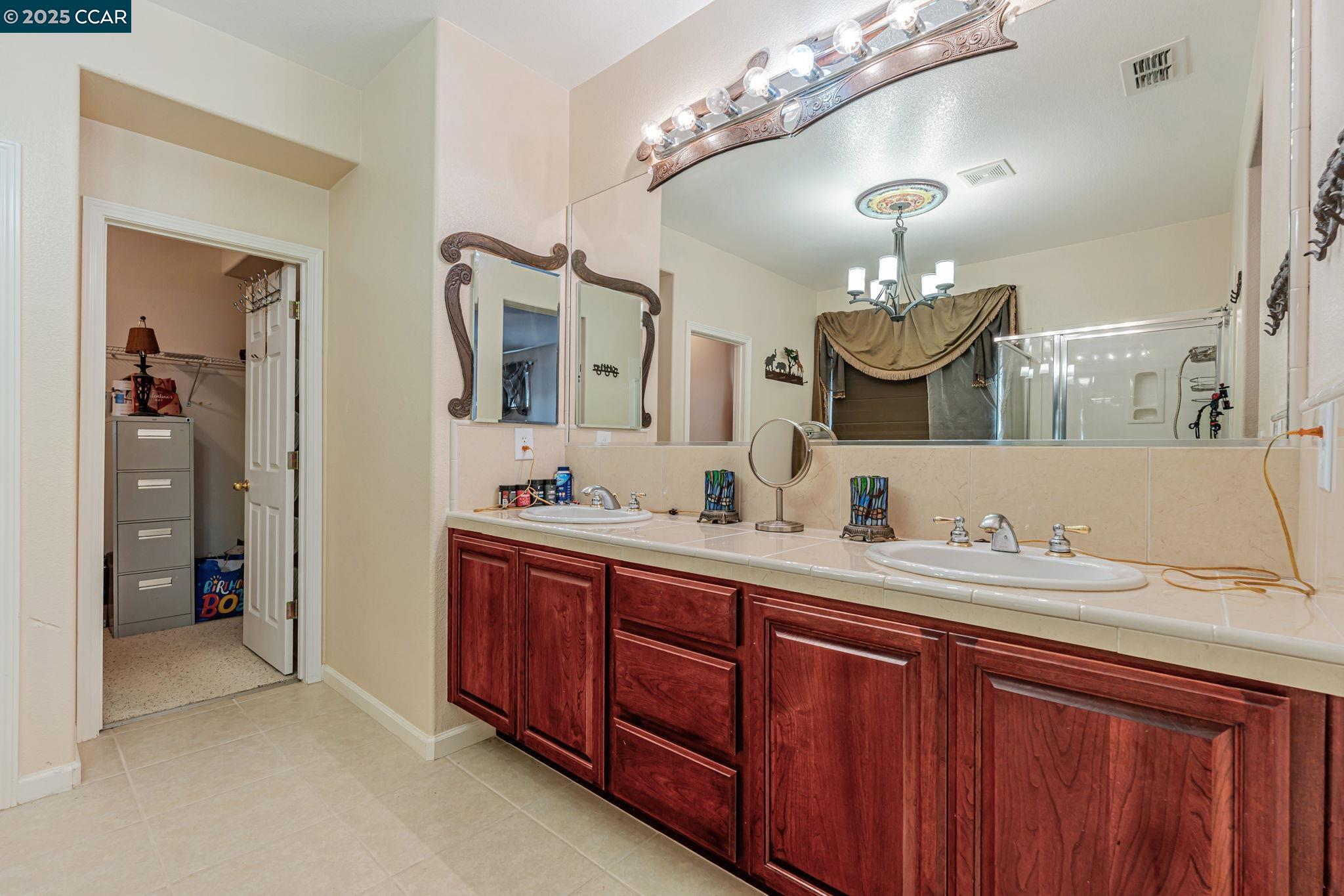 20640 Sarazen Place Patterson, CA 95363 - Photo 16 of 28 a bathroom with a double vanity sink and a mirror